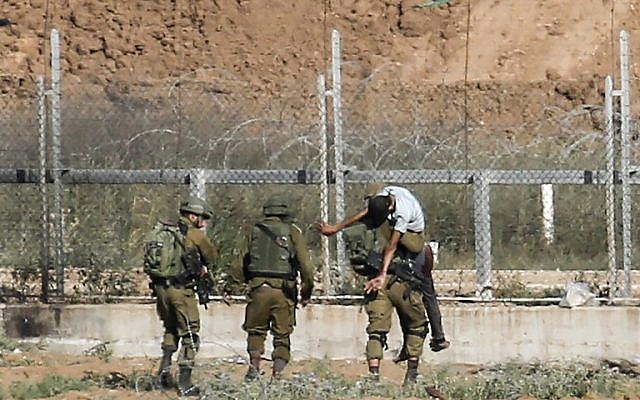 Des soldats israéliens emmènent un Palestinien blessé qui, selon l'armée, a tenté de franchir la barrière frontalière à l'est de Jabaliya, dans le nord de la bande de Gaza, le 27 juin 2018. (Crédit : Saïd Khatib/AFP)