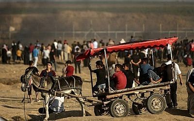 De jeunes hommes se déplacent à bord d'une charrette tirée par un âne pendant les affrontements entre les manifestants palestiniens et les soldats israéliens à l'est de la ville de Gaza, le long de la frontière entre la bande de Gaza et Israël, le 29 juin 2018. (AFP PHOTO / MAHMUD JAMBON)