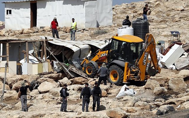 La police israélienne sécurise un bulldozer démolissant des installations dans le village bédouin d'Abu Nuwar, à l'est de Jérusalem, en Cisjordanie, le 4 juillet 2018. (AHMAD GHARABLI/AFP)