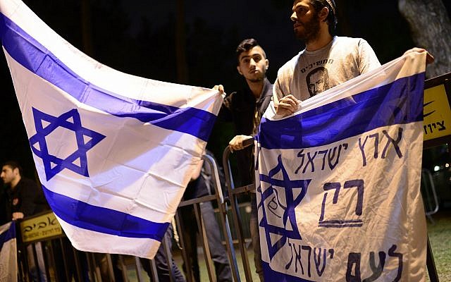 Des militants de droite israéliens protestent aux abords d'une cérémonie conjointe pour les familles de victimes israéliennes et palestiniennes lors de la Journée israélienne de commémoration, le 21 avril 2015 Le drapeau dit : "La terre d'Israël pour les Israéliens seulement" (Crédit : Tomer NeubergFlash90)