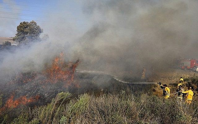 Les pompiers éteignent un incendie à proximité de Sdérot, dans le sud du pays, causé par un ballon incendiaire de la bande de Gaza, le 31 juillet 2018 (Crédit : AFP Photo/Menahem Kahana)