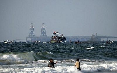 Des bateaux palestiniens participent à une manifestation contre le blocus de sécurité israélo-égyptien de Gaza, à Beit Lahya, à la frontière avec Israël dans le nord de la bande de Gaza, le 11 août 2018. La centrale électrique israélienne de Rutenberg est visible à l'arrière-plan. (AFP PHOTO / MAHMUD JAMBON)