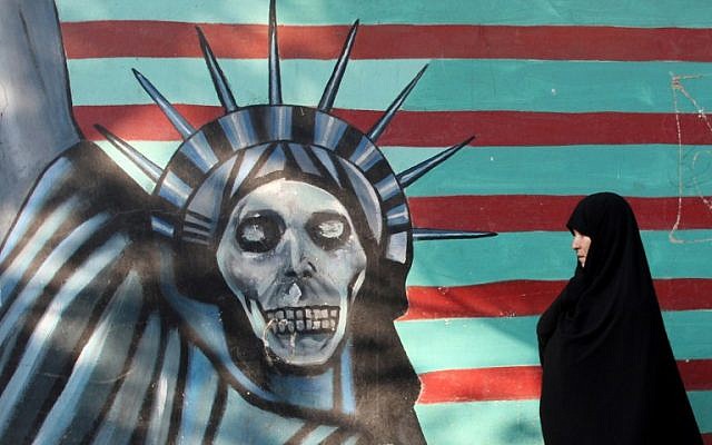 Une Iranienne promène son chien devant une fresque sur le mur de l'ancienne ambassade américaine à Téhéran, le 9 novembre 2016. (Crédit : AFP/Atta Kenare)