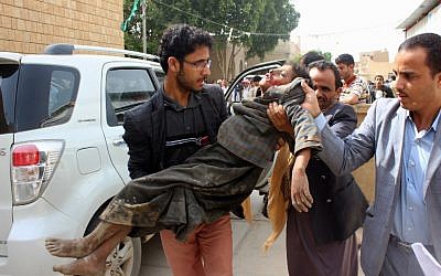 Un enfant yéménite emporté vers un hôpital après avoir été blessé lors d'une attaque aérienne présumée contre le bastion des Houthis soutenus par Iran dans la province de Saada, le 9 août 2018 (Crédit :  AFP)