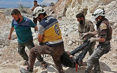 A Kafr Ain, des membres de la Défense civile syrienne, connus sous le nom de Casques blancs, transportent une victime après des frappes aériennes à 4 kilomètres à l'est de Khan Shaykhun idans le sud de la province d'Dlib, le 7 septembre 2018 (Crédit : AFP PHOTO / Anas AL-DYAB)