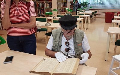 Yoram Sztykgold examine l'annuaire de 1939 qui l'a aidé à localiser les biens de sa famille dans une librairie de Varsovie, le 4 septembre 2018 (Crédit : Cnaan Liphshiz)