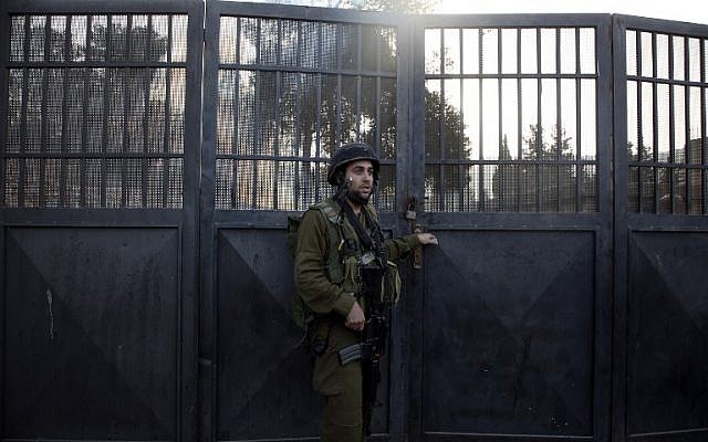 Un soldat israélien monte la garde devant une école palestinienne fermée par Israël, en Cisjordanie, le 16 octobre 2018. (Crédit : JAAFAR ASHTIYEH / AFP)