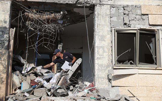 Les forces de sécurité israéliennes inspectent un bâtiment qui a été touché par une roquette tirée depuis la bande de Gaza dans la ville de Beer Sheva dans le sud d'Israël, le 17 octobre 2018. (Yonatan Sindel/Flash90)