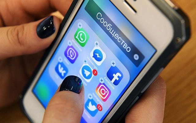 Une femme tient un smartphone avec les icônes des réseaux sociaux  Facebook, Instagram, Twitter et autres à Moscou, le 23 mars 2018. (Crédit : Kirill KUDRYAVTSEV/AFP)