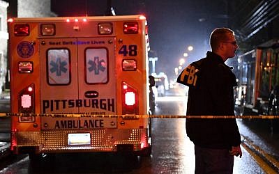 Un agent du FBI et une ambulance derrière le cordon de la police aux abords de la synagogue Tree of Life, à gauche, après la fusillade qui a fait 11 morts dans le quartier de Squirrel Hill de Pittsburgh, le 27 octobre 2018 (Crédit :  Brendan Smialowski / AFP)