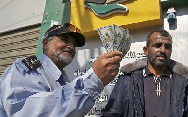 Un Palestinien montre son argent après avoir reçu son salaire à Rafah dans le sud de la bande de Gaza, le 9 novembre 2018 (Crédit : Said Khatib/AFP)