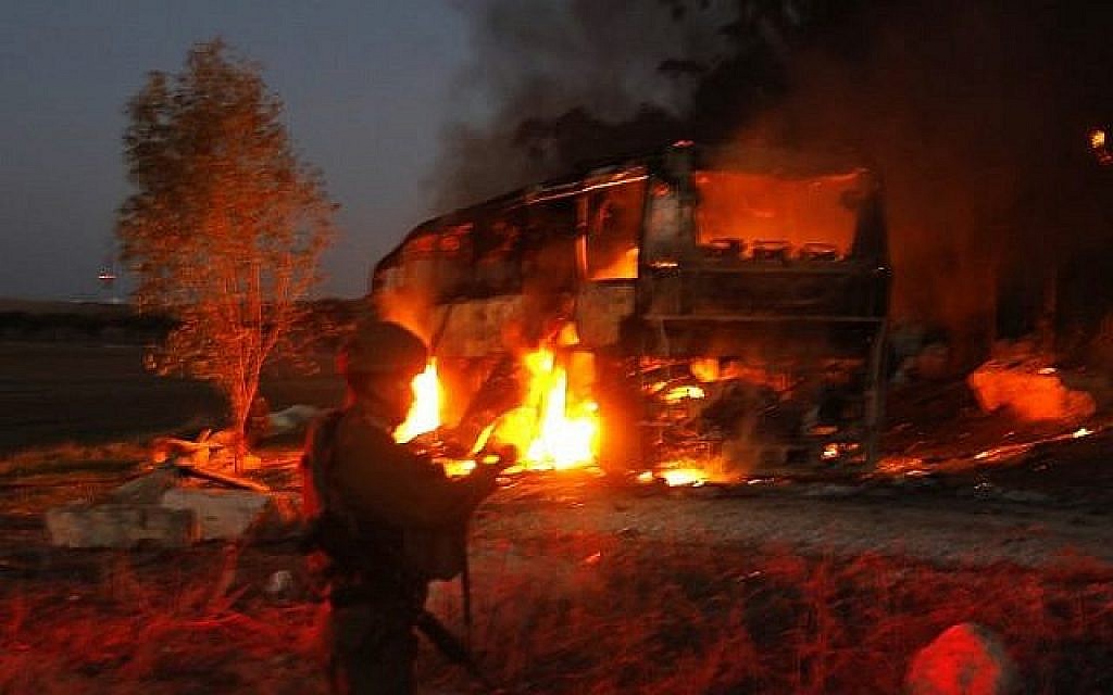 Les forces de sécurité israéliennes et les pompiers se rassemblent près d'un bus incendié touché par un missile anti-char tiré depuis l'enclave palestinienne, à la frontière entre Israël et Gaza près du kibboutz de Kfar Aza, le 12 novembre 2018. (Crédit :  Menahem KAHANA / AFP)