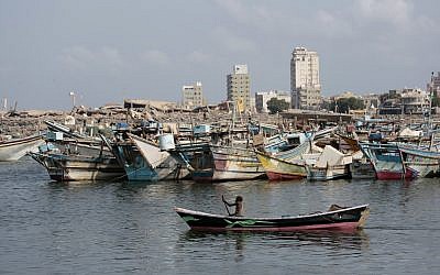Un bateau de pêcheurs navigue devant le port d'Hodeida. En arrière-plan, les immeubles détruits par la coalition soutenue par l'Arabie saoudite et les Emirats arabes unis, le 28 septembre 2018 (Crédit : AP/Hani Mohammed)