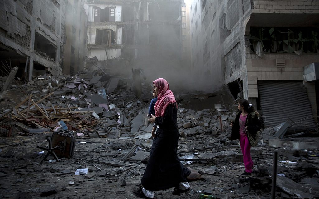 Une femme palestinienne passe à proximité d'un immeuble résidentiel détruit, frappé par des frappes aériennes israéliennes dans la ville de Gaza, le mardi 13 novembre 2018. (Crédit : AP / Khalil Hamra)