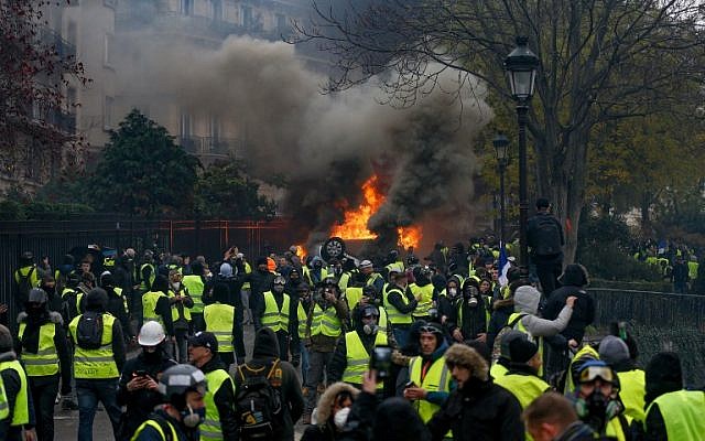 Des manifestants se rassemblent autour d'une voiture en feu lors d'une manifestation des Gilets jaunes contre la hausse du prix du pétrole et du coût de la vie, le 1er décembre 2018 à Paris. (Geoffroy VAN DER HASSELT / AFP)