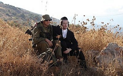 Des soldats du bataillon ultra-orthodoxe Netzah Yehuda de l'armée israélienne sont assis dans un champ sur la base militaire de Peles, dans la vallée du Jourdain. (Yaakov Naumi/Flash90)