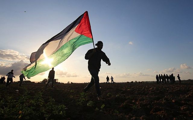 Un manifestant palestinien porte un drapeau national lors d'une manifestation près de la frontière entre Israël et Khan Younès dans le sud de la bande de Gaza, le 21 décembre 2018. (Photo par SAID KHATIB / AFP)