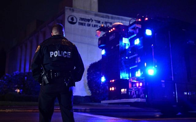 Un agent de police sous la pluie aux abords de la synagogue Tree of Life après une fusillade qui a fait onze morts dans le quartier de Squirrel Hill à  Pittsburgh le 27 octobre 2018 (Crédit : Brendan Smialowski / AFP)
