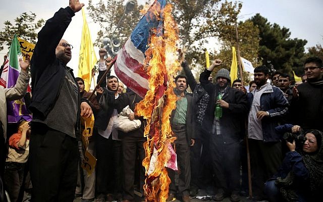 Les manifestants iraniens brûlent un drapeau américain pendant un rassemblement anti-américain annuel à Téhéran, en Iran, le 4 novembre 2013 (Crédit : Ebrahim Noroozi/AP)
