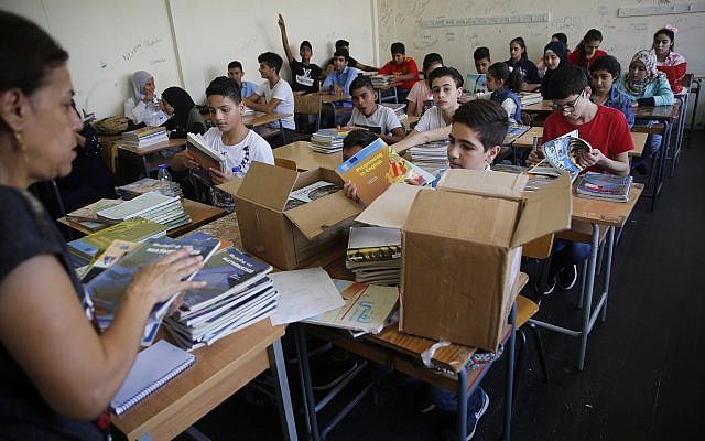 Des écoliers palestiniens reçoivent de nouveaux manuels dans leur classe lors de la rentrée de cette année dans l’une des écoles de l’UNRWA à Beyrouth au Liban, le 3 septembre 2018. (Crédit : Hussein Malla/AP)