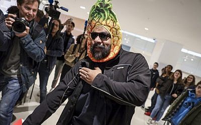 Dieudonné M'Bala M'Bala, portant un masque représentant un ananas en référence à son expression négationniste "shoahananas", fait le geste controversé de la "quenelle" à son arrivée au palais de justice de Paris, le 26 mars 2019, devant un public amusé. (Crédit : KENZO TRIBOUILLARD / AFP)