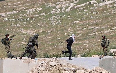 Un soldat de l'armée israélienne pourchasse un suspect palestinien tentant de fuir dans la ville de Tuqu, en Cisjordanie, le 18 avril 2019 (Crédit :Mohammad Hmeid)