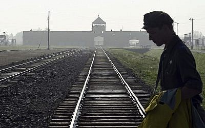 Dans cette photo du 29 juillet 2016, un homme traverse la tristement célèbre voie ferrée de l'ancien camp de la mort nazi d'Auschwitz-Birkenau en Pologne. (AP Photo/Alik Keplicz, FILE)