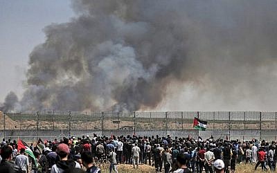 Des manifestants palestiniens participent à des émeutes le long de la barrière de sécurité à l'est de la ville de Gaza alors que de la fumée s'envole dans le ciel. L'incendie a été provoqué par un engin incendiaire attaché à un cerf volant envoyé de l'autre côté de la frontière vers Israël depuis la bande de Gaza, le 15 mai 2019. (Crédit : MAHMUD HAMS / AFP)