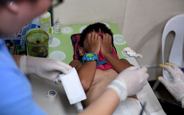 Un enfant se crispe de douleur pendant une procédure de circoncision à Manille, à le 10 mai 2019. (Crédit : Noel CELIS / AFP)