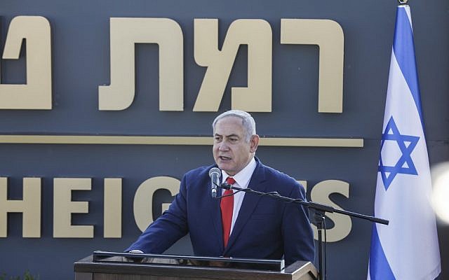 Le Premier ministre Benjamin Netanyahu prononce un discours devant le panneau de la nouvelle communauté établie au nom de "Ramat Trump", "colline  Trump" en français, qui porte le nom du président américain, durant une cérémonie officielle, le 16 juin 2019 (Crédit : Jalaa MAREY/AFP)