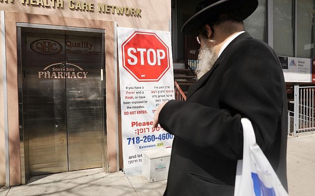 Un panneau mettant en garde la communauté juive ultra-orthodoxe contre une épidémie de rougeole devant une parmacie du quartier de Williamsburg, le 10 avril 2019. (Crédit : Spencer Platt/Getty Images/AFP)