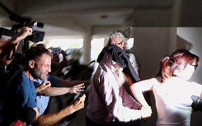 Un agent de police escorte une jeune femme britannique de 19 ans, au centre, vers le tribunal de Famagouste, à Paralimni, à Chypre, le 29 juillet 2019 (Crédit : AP Photo/Petros Karadjias)