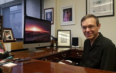 Le Professeur Avi Loeb dans son bureau à Harvard. Son fond d'écran contient une photo de Proxima Centauri, l'étoile la plus proche de notre Soleil. (Rich Tenorio/Times of Israel)