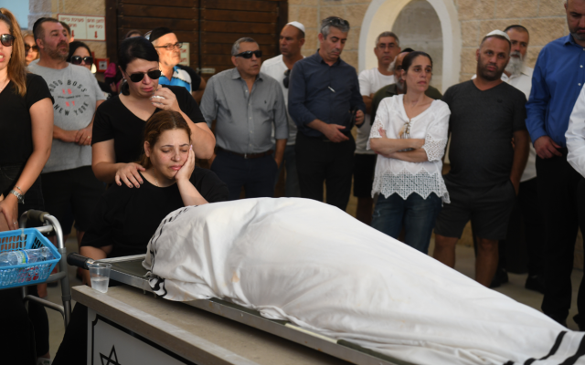 Dikla Hasdai se recueille près du corps de son mari, Ofir Hasdai  qui a été abattu dans un parking de Ramle, lors de ses funérailles au cimetière de Ramle, le 29 juillet 2019. (Avi Dishi/Flash90)