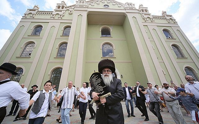 Yaakov Dov Bleich portant des rouleaux de la Torah dans la synagogue Drohobycz en Ukraine, le 3 juillet 2019. (Credit : Rephael Isaak Vilenskiy/JTA)
