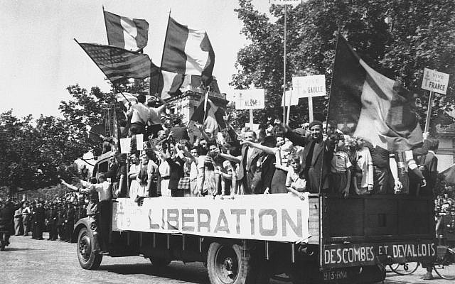 Un camion chargé de Parisiens qui brandissent des drapeaux français et américains et de panneaux "Vive De Gaulle" dans un paris en liesse, après sa libération,le 28 août 1944. (Crédit : AP Archives)