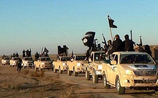 Sur cette photo d'archive non datée publiée par un site Web militant, qui a été vérifiée et qui correspond à d'autres rapports de l'AP, des djihadistes du groupe État islamique brandissent leurs armes et agitent ses drapeaux sur leurs véhicules dans un convoi vers l'Irak, à Raqqa, en Syrie. (Crédit : Site web militant/ AP)