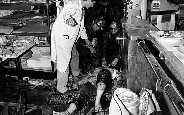 Des pompiers et des infirmières s'occupent d'un blessé derrière le comptoir d'un restaurant juif Jo Goldenberg, situé dans la rue des Rosiers à Paris, après l'attaque terroriste perpétrée par des hommes armés dans le restaurant, le 9 août 1982. L'attaque a fait six morts et de nombreux blessés. (AP Photo/ Aulnay)