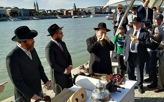 Le rabbin Baruch Oberlander, à droite, souffle dans le shofar au bord des rives du Danuble lors d'une cérémonie pour la consécration d'une nouvelle synagogue et d'un rouleau de Torah à Szentendre, en Hongrie, le 22 septembre 2019 (Crédit : Yaakov Schwartz/ Times of Israel)