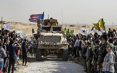 Les Kurdes syriens se réunissent autour d'un blindé américain durant une manifestation contre les menaces de la Turquie près d'une base de la coalition internationale dirigée par les Etats-Unis aux abords de Ras al-Ain, dans la province de Hasakeh, en Syrie, près de la frontière turque, le 6 octobre 2019. (Crédit : Delil Souleiman/AFP)
