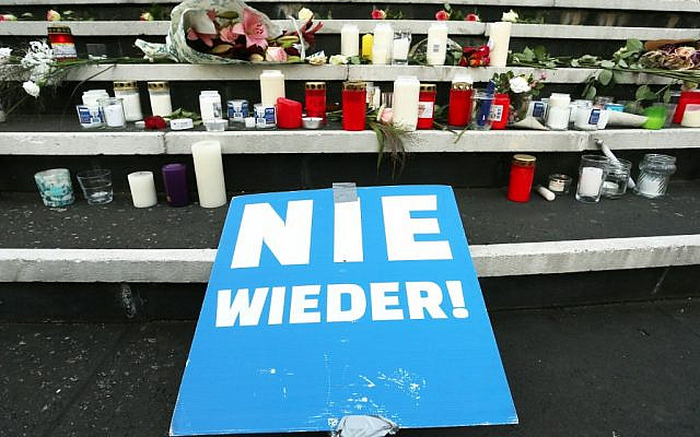 Une affiche disant "plus jamais !", des bougies et des fleurs devant un mémorial improvisé à la synagogue de  Duesseldorf, à l'ouest de l'Allemagne, au lendemain d'une fusillade meurtrière antisémite à Halle, le 10 octobre 2019 (Crédit :  David Young/DPA/AFP)