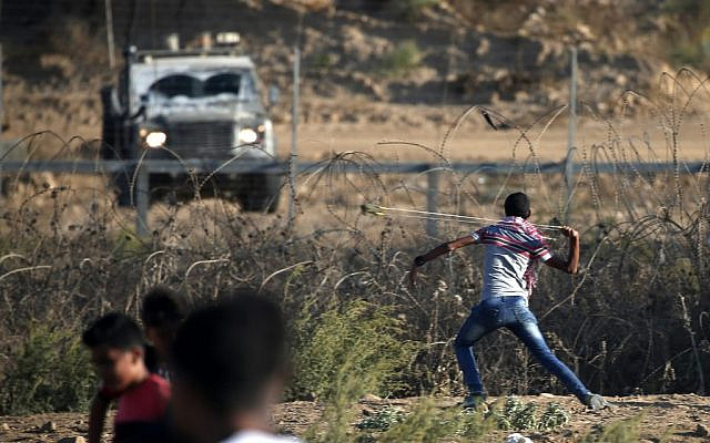 Illustration : Un Palestinien armé d'une fronde fjette des pierres aux forces israéliennes durant une émeute le long de la frontière avec Israël, à l'est de Bureij, dans le centre de la bande de Gaza, le 18 octobre 2019 (Crédit : Mahmud Hams/AFP)