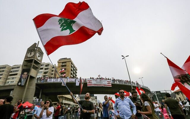 Un homme brandit un drapeau du Liban durant une manifestation sur l'autoroute qui relie Beyrouth à Tripoli, pendant des manifestations contre l'augmentation des impôts et la corruption au sein du gouvernement, le 26 octobre 2019. (Crédit : JOSEPH EID / AFP)