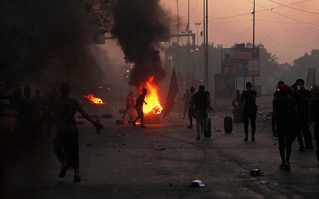 Des manifestants anti-gouvernement allument un incendie et ferment une rue près de Bagdad, en Irak, pendant une manifestation, le 5 octobre 2019 (Crédit : AP Photo/Hadi Mizban)