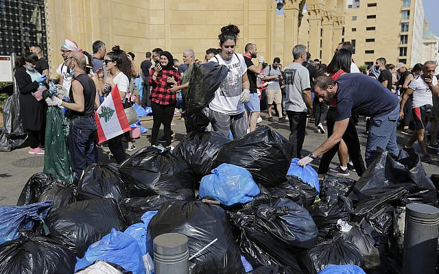 Des bénévoles aident à nettoyer les rues après les manifestations violentes contre le gouvernement libanais à Beyrouth, au Liban, le 21 octobre 2019 (Crédit : AP Photo/Hassan Ammar)