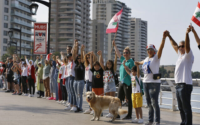 Des manifestants libanais forment une chaîne humaine et bloquent l'un des principaux pont de Beyrouth, lors de manifestations contre le gouvernement, le 26 ocotbre 209. (Crédit : STR / AFP)