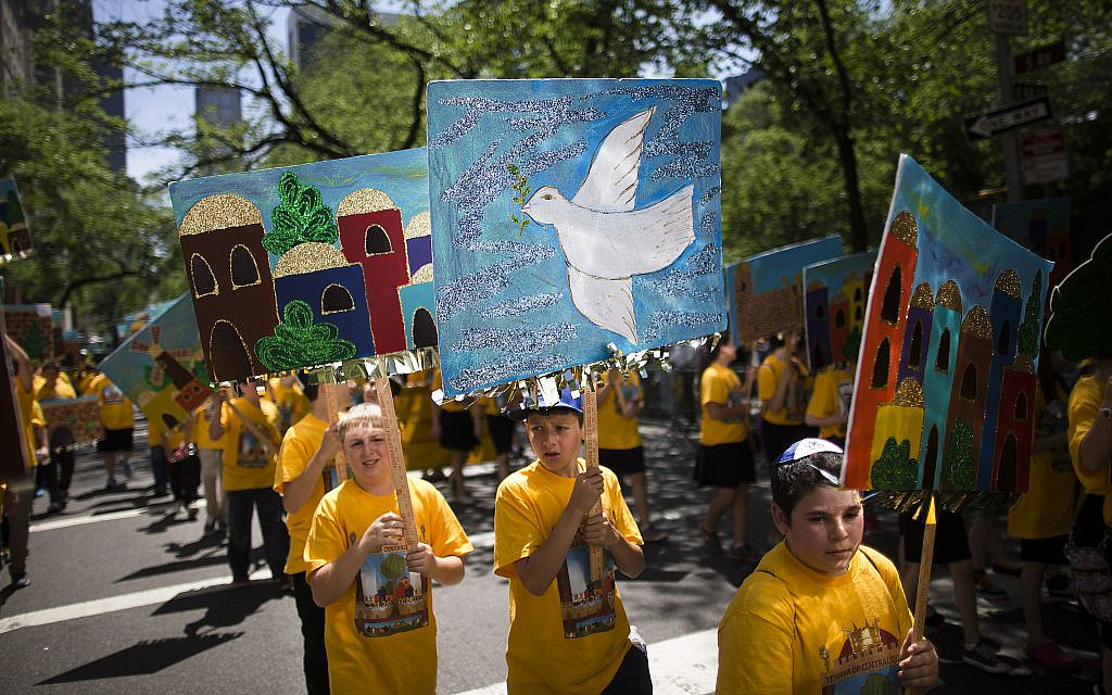 Un jeune garçon porte un panneau représentant une colombe de la paix avec d'autres élèves d'une école juive pendant le défilé Celebrate Israel à New York, le dimanche 1er juin 2014. (AP Photo/John Minchillo)
