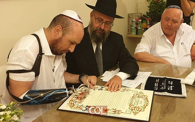 Ben Spitzer, le soldat le plus gravement blessé de l'opération Plomb durci contre Gaza, signe sa ketouba avant son mariage à Ashkelon, le 7 octobre 2019. (Crédit : Chabad Youth Organization)