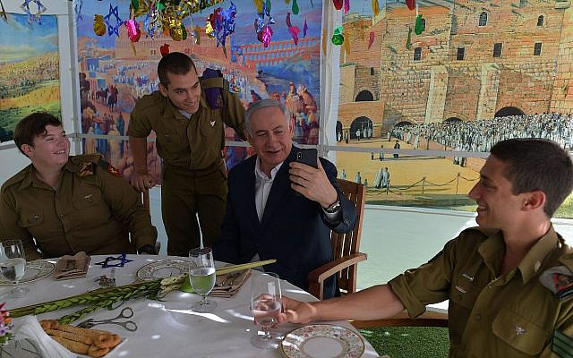 De gauche à droite : Le caporal Aleksandra Vodenskov, le sergent Alexander Sachs, le Premier ministre Benjamin Netanyahu et le sergent Eddie Laufer idans la souccah du Premier ministre à Jérusalem, le 13 octobre 2019 (Crédit : Koby Gideon/GPO)