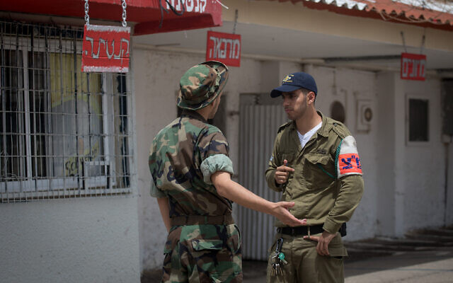 Un officier de la police militaire israélienne, à droite, parle avec un soldat emprisonné à la Prison Quatre, la plus grande prison militaire d'Israël, sur la base militaire Tzrifin, dans le centre d'Israël, le 26 avril 2018. (Miriam Alster/FLASH90)